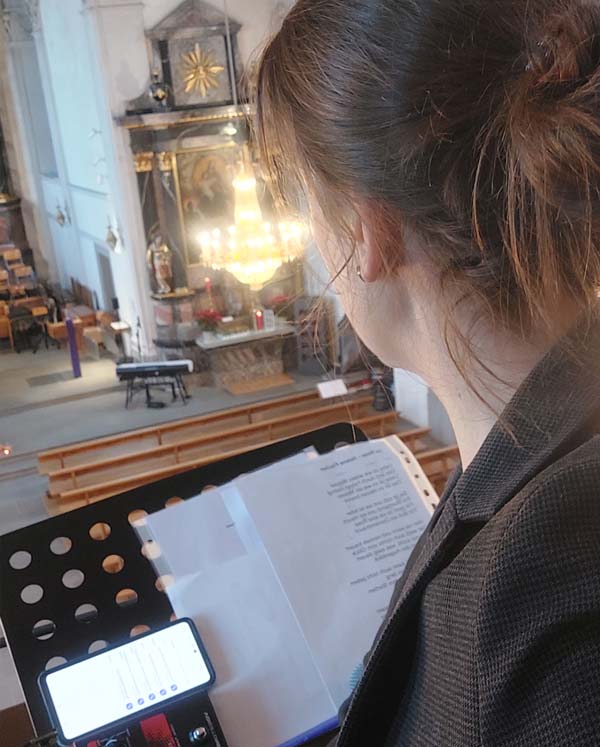 Sängerin bei der Trauerfeier in der Kirche St. Johannes Walchwil, singend von der Empore mit Blick auf den Altar, Notenständer und Handy im Vordergrund